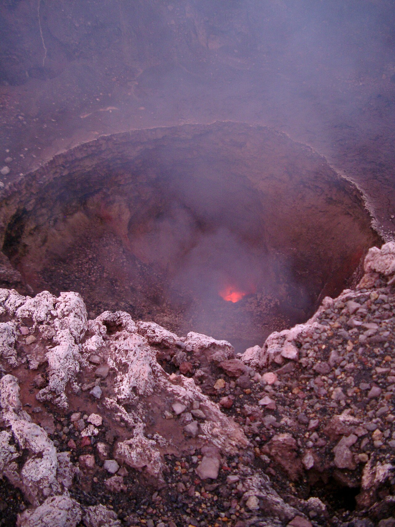 The pit crater of Masaya volcano, Nicaragua, in 2003. Glow from an open vent to the magma below; fume of volcanic acid sulphate droplets.